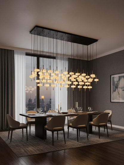 A modern dining room showcases a large rectangular table, eight upholstered chairs, elegant place settings, and the striking SpaceAge Chandelier. Floor-to-ceiling windows reveal city views, while gray walls are adorned with framed abstract art.