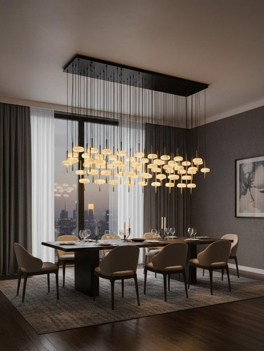 A modern dining room showcases a large rectangular table, eight upholstered chairs, elegant place settings, and the striking SpaceAge Chandelier. Floor-to-ceiling windows reveal city views, while gray walls are adorned with framed abstract art.
